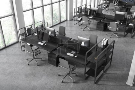 Foto de Vista superior del interior de coworking con ordenadores PC en escritorio de madera negro, sillas en fila en piso de hormigón gris. Elegante espacio de trabajo con muebles minimalistas y ventana panorámica. Renderizado 3D - Imagen libre de derechos