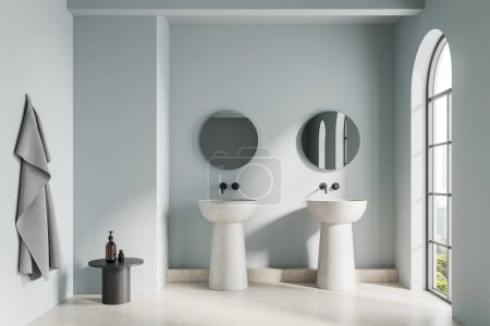Blue hotel bathroom interior with stone double sink, two round mirrors and table with accessories, towel. Panoramic arched window on Bangkok skyscrapers. 3D rendering