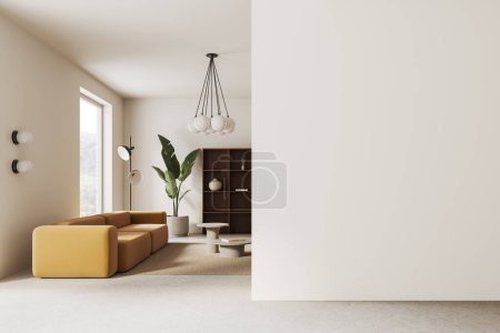 Foto de Interior de la elegante sala de estar con paredes blancas, suelo de hormigón, cómodo sofá amarillo de pie cerca de la mesa de café y la pared del espacio de copia a la derecha.. - Imagen libre de derechos