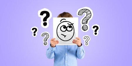 Photo for Boy holding sheet of paper with pensive emoticon doodle, question marks sketch on purple background. Making up ideas and problem solving. Concept of education, thoughts and answers - Royalty Free Image