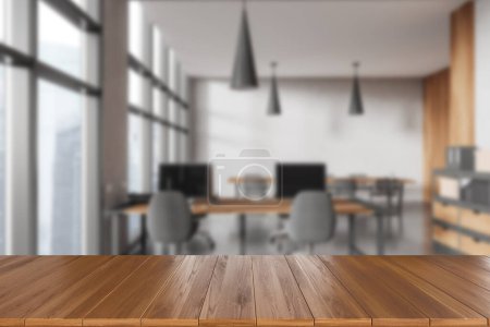 Photo for Empty wooden desk on foreground, background of blurred coworking interior with armchairs and pc computer, office loft with panoramic window. Mockup for product display. 3D rendering - Royalty Free Image