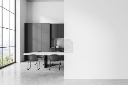 Téléchargez les photos : Intérieur d'une cuisine élégante avec des murs blancs, sol en béton, placards et armoires gris confortables, longue table à manger avec des chaises grises et un mur d'espace de copie sur la droite. Rendu 3d - en image libre de droit
