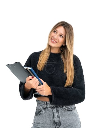 Photo for Dreaming student woman holding clipboard and notebook in hands, looking aside isolated over white background. Concept of education, plans and future career - Royalty Free Image