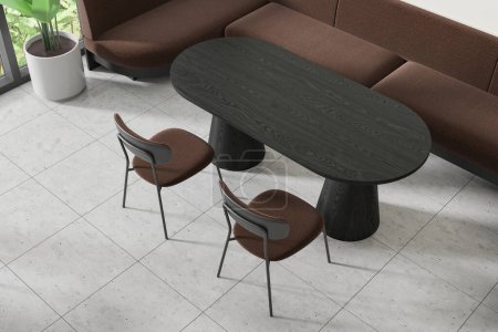 Foto de Un moderno interior de cafetería con una mesa ovalada negra, sillas elegantes, un sofá y una planta, contra un suelo de baldosas, con luz que viene de un lado. Renderizado 3D - Imagen libre de derechos