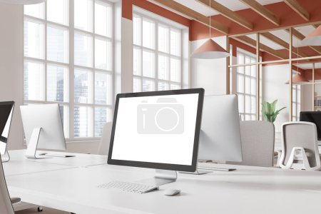 Téléchargez les photos : Vue en angle de l'intérieur du lieu de travail avec écran blanc d'ordinateur PC maquette, zone de coworking avec des tables en rangée. Fenêtre panoramique sur les gratte-ciel de Singapour. rendu 3D - en image libre de droit