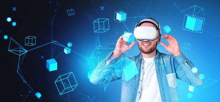 Foto de Un hombre con auriculares VR interactuando con elementos gráficos digitales futuristas sobre un fondo azul, concepto de realidad virtual - Imagen libre de derechos