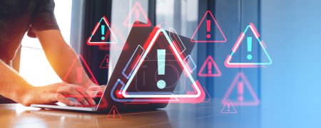 Photo for Person typing on a laptop with holographic warning symbols on screen in an office environment, concept of cybersecurity threat - Royalty Free Image