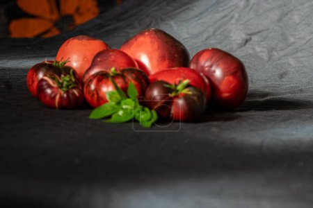 Foto de Tomates coloridos, jugosos y saludables sobre un fondo oscuro, una nutrición sabrosa y saludable, adecuada para vegetarianos - Imagen libre de derechos