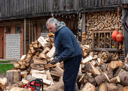 A man works with an ax in his yard, processing firewood for the winter season, burning firewood, heating firewood in the countryside
