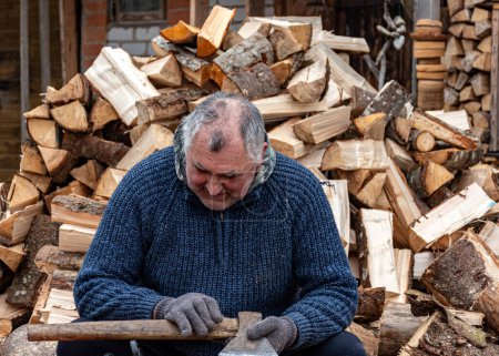 Un homme travaille avec une hache dans sa cour, transformant du bois de chauffage pour la saison hivernale, brûlant du bois de chauffage, chauffant du bois de chauffage à la campagne