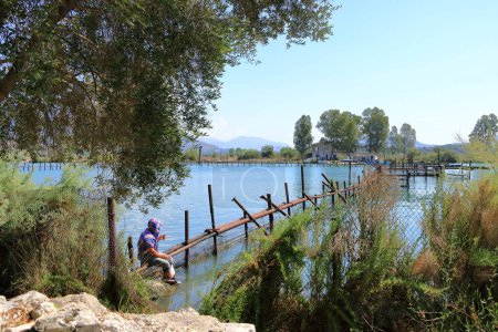 Téléchargez les photos : 17 septembre 2023 - Butrint en Albanie : Un pêcheur albanais sur la lagune salée du lac Butrint, vue depuis le parc national de Butrint, le célèbre site du patrimoine mondial de l'UNESCO - en image libre de droit