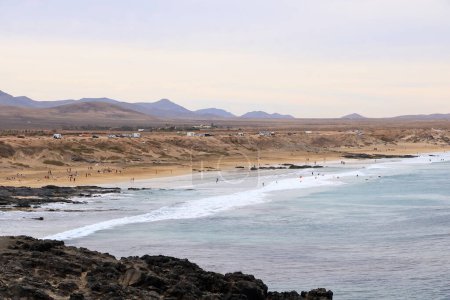 El Cotillo, Fuerteventura, Canary Islands, Spain - November 21 2023: people enjoy the stunning view of beach with a rocky coastline on a cloudy day