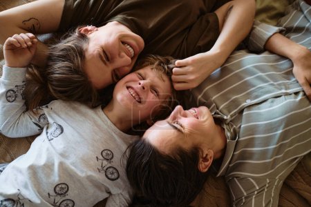 Foto per Vista ad alto angolo della felice famiglia lesbica con piccolo figlio che si rilassa sul letto insieme - Immagine Royalty Free