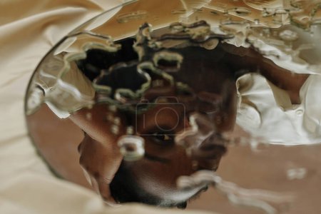 Photo for Close-up of reflection of young African woman looking through drops in mirror - Royalty Free Image