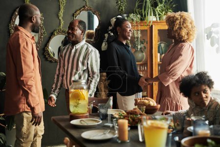 Afrikanische große Familie unterhält sich und freut sich, einander zu sehen, während sie sich beim gemeinsamen Abendessen im Speisesaal trifft