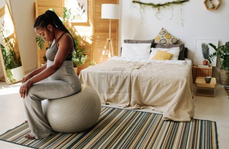 Photo for African young woman sitting on fitness ball and concentrating on her pain during contractions - Royalty Free Image