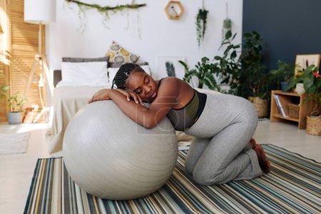 Foto de Mujer embarazada joven que se apoya en la pelota de fitness durante las contracciones que sufren de dolor - Imagen libre de derechos