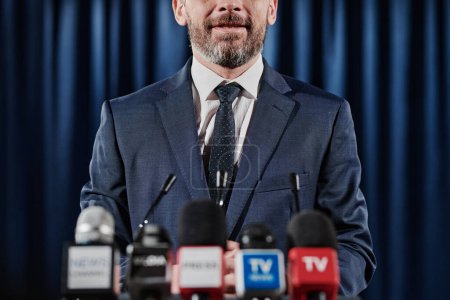 Foto de Primer plano del orador barbudo en traje formal hablando por televisión en conferencia de prensa - Imagen libre de derechos