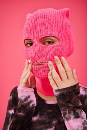 Photo for Portrait of young woman in pink balaclava with sewed mouth looking at camera, she fighting for women rights - Royalty Free Image