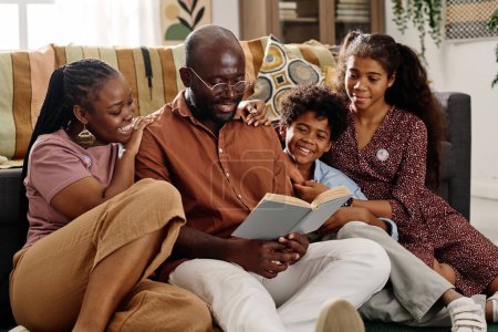 Photo for Father of family reading book on Martin Luther King Jr ideas to his wife and two kids - Royalty Free Image
