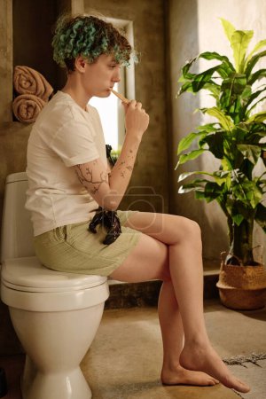 Photo for Pensive girl with bionic arm brushing teeth in morning - Royalty Free Image
