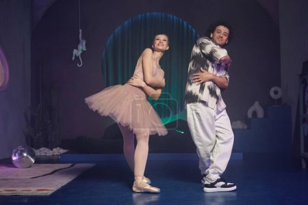Téléchargez les photos : Ballerine souriante et jeune homme joyeux faisant figure de ballet ensemble dans l'espace de l'art contemporain - en image libre de droit