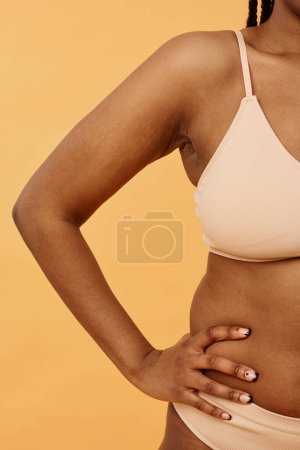 Studio shot of unrecognizable confident Black woman wearing minimalistic lingerie posing for camera with hand on hip