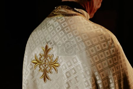 Vue arrière gros plan moyen d'un prêtre catholique méconnaissable vêtu de dalmatisme debout dans une église