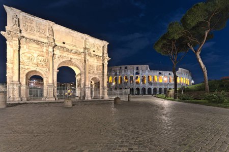 Photo for View on the Collosseum and the Arco di Costantino at night time. Only one indistinguishable person is sitting on a bench. - Royalty Free Image