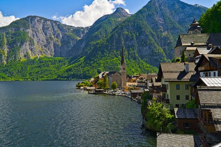 A small town is located on a small island in the middle of a lake with majestic mountains in the background, creating a picturesque natural landscape
