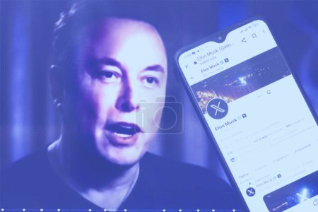 Foto de Ucrania, 2023. Elon Musk perfil de Twitter en un teléfono inteligente y Elon Musk en el fondo. - Imagen libre de derechos