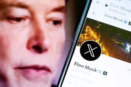 Foto de Elon Musks perfil de Twitter en un teléfono inteligente y Elon Musk en el fondo. - Imagen libre de derechos
