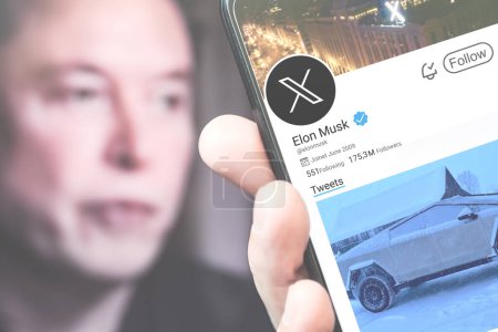 Téléchargez les photos : Poltava, Ukraine - 6 mars 2024 : Elon Musk Page de profil Twitter sur un écran de smartphone avec un nouveau tweet. En arrière-plan se trouve un portrait flou d'Elon Musk. Concentration douce. - en image libre de droit