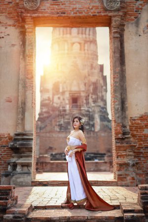 Young fashion and beautiful asian woman wearing Thai traditional costume standing in ancient temple Ayutthaya, Thailand