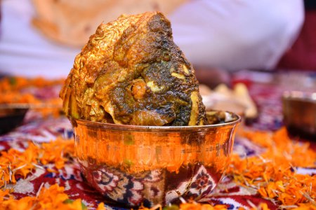 Picture of a large cooked cuttlefish head on the bell-metal bowl Indian meal (Thali) decorated by flowers.