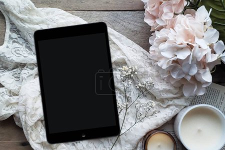 Une couche plate confortable avec une écharpe grise, une tasse de chocolat chaud et une tablette sur un fond de table en bois de grange pour un concept de lecture confortable.