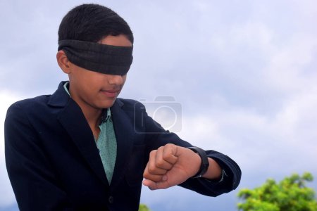 Photo for 13 year old child with blindfold watching time on clock, Indecision and uncertainty conceptual, cloudy background - Royalty Free Image