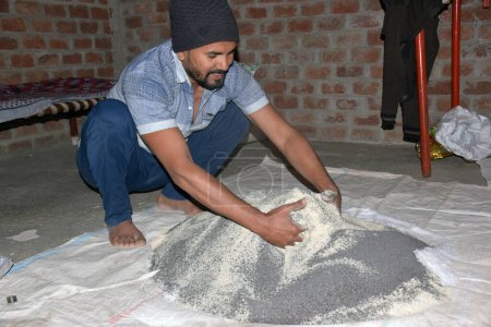 Téléchargez les photos : Fermier indien mélangeant différents éléments d'engrais dans le fumier, à la maison. focus sélectif - en image libre de droit