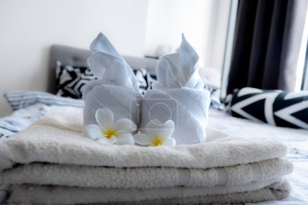 Plumeria and towels on the bed in the luxury hotel room ready for tourist travel.