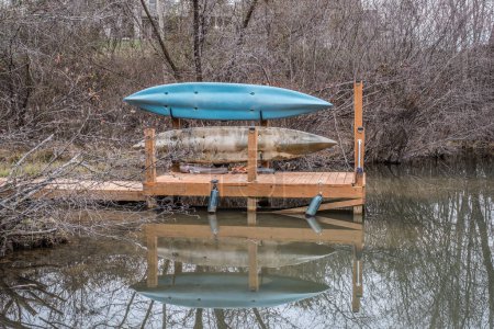 Foto de Dos kayaks almacenados en el lado entre paréntesis en un muelle en el lago con un reflejo en el agua en invierno - Imagen libre de derechos