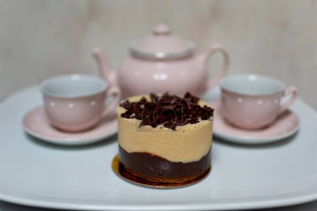 Foto de Fiesta de té, con tetera, tazas de té y mini pastel gourmet - Imagen libre de derechos