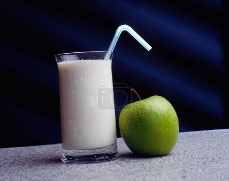 Téléchargez les photos : Verre de lait avec paille et pomme verte fraîche sur la surface grise - en image libre de droit