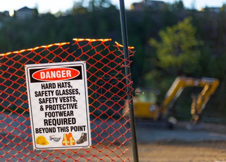 Plastic chain-link fence at construction site with sign notifying safety gear required at Still Pond; Kelowna, British Columbia, Canada