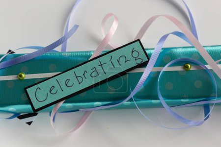 Close-up of ribbons, decorations, gift wrap and a sign saying celebrating