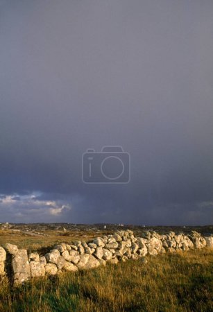 Foto de Muro de piedra en el campo bajo cielos tormentosos; Condado de Gorumna Island Galway Irlanda - Imagen libre de derechos
