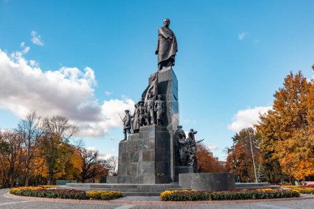Taras Shevchenko Monument in Kharkiv city center park on blue sky with clouds background. Autumn vibes, colorful flowerbed and trees in Shevchenko City Garden, Ukraine