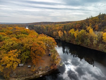 Aerial autumn river turn with colorful trees on riverbanks and clouds reflections. Autumnal Siverskyi Donets River in Ukraine