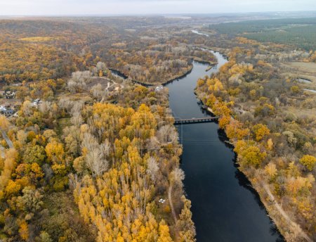 Luftaufnahme einer Brücke über den Fluss mit gelben Herbstbäumen und Erholungsgebiet in Korobovy Hutora (Dorf Koropove) in der Ukraine
