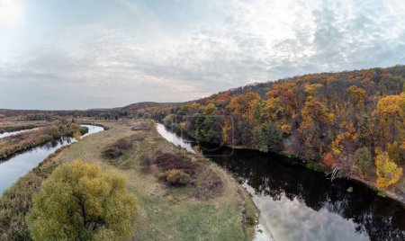 Aerial trees on Siverskyi Donets river shore panorama with autumn forest and cloudy sky in Ukraine