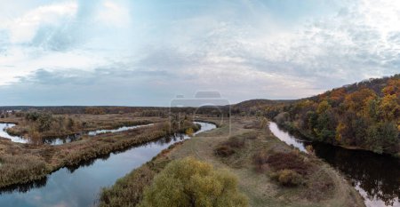 Aerial trees on Siverskyi Donets river valley panorama with autumn forest and cloudy sky in Ukraine